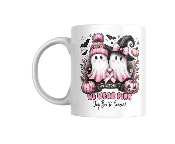 Weiße Tasse mit zwei süßen Geistern, von denen einer eine rosa Mütze und der andere einen Hexenhut trägt, beide mit rosa Schleife für den Kampf gegen Brustkrebs. Dekoriert mit Kürbissen, Fledermäusen und dem Text ‚We Wear Pink – Say Boo to Cancer‘. Ideal