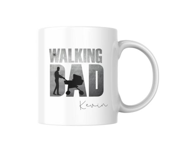 Eine weiße Tasse mit dem Schriftzug "The Walking Dad" zeigt die Silhouette eines Vaters, der einen Kinderwagen schiebt. Unter dem Motiv steht der Name "Kevin". Die Tasse hat ein modernes Design und eignet sich hervorragend als persönliches Geschenk für Vä
