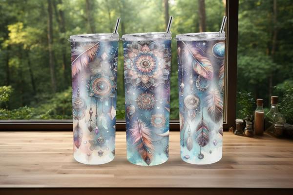 Drei Thermobecher mit spirituellem Design aus Traumfängern, Federn, Mandalas und geometrischen Symbolen in Blau- und Beigetönen. Die Becher stehen auf einer Holzoberfläche mit einem Wald im Hintergrund, was dem Bild eine ruhige und mystische Atmosphäre ve