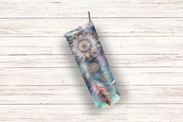 Ein Thermobecher mit einem detailreichen, mystischen Design aus Mandalas, Federn und geometrischen Symbolen in sanften Blau- und Beigetönen, schräg auf einem hellen Holzuntergrund liegend. Das Design vermittelt eine beruhigende, spirituelle Atmosphäre, id