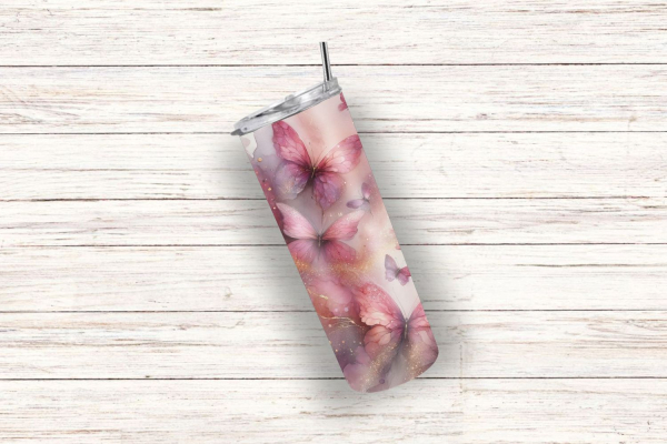 Thermobecher auf einem weißen, strukturierten Holzhintergrund. Das Design zeigt zarte, rosa Schmetterlinge, die auf einem pastellfarbenen Hintergrund schweben, umgeben von feinen goldenen Details und nebligen Akzenten für einen träumerischen, luftigen Loo