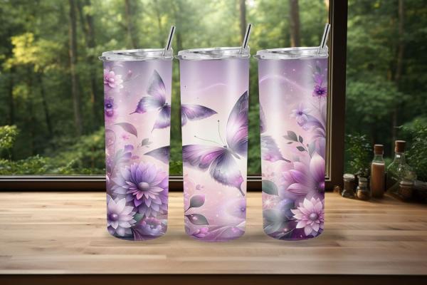 Drei Thermobecher mit einem eleganten Design von violetten Schmetterlingen und großen, detaillierten Blumen stehen auf einer Holzoberfläche vor einem Fenster mit einem Blick ins Grüne. Der Hintergrund ist unscharf und zeigt eine friedliche Waldszene, die