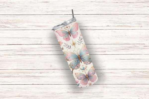 Ein schlanker Thermobecher mit einem verspielten Schmetterlingsdesign auf einem cremefarbenen Hintergrund. Der Becher ist mit großen, pastellfarbenen Schmetterlingen in Rosa- und Blautönen sowie kleinen Blumen und zarten goldenen Details verziert. Das Des