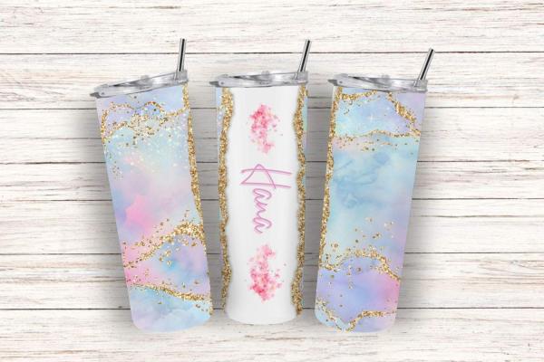 Drei elegante Thermobecher mit pastellfarbenem Design in Rosa, Blau und Lila, verziert mit goldenen Glitzer-Details. Der mittlere Becher zeigt den Namen 'Hana' in pinker Schrift auf einem weißen Hintergrund mit zarten Blumenmotiven. Die Becher stehen auf