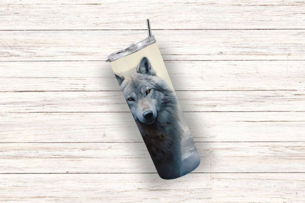 Ein einzelner Thermobecher mit einem eindrucksvollen Wolfsmotiv, das das Gesicht eines grauen Wolfs mit aufmerksamem Blick zeigt. Der Becher hat einen silbernen Deckel und Edelstahlstrohhalm und ist auf einem hellen Holz-Hintergrund positioniert.