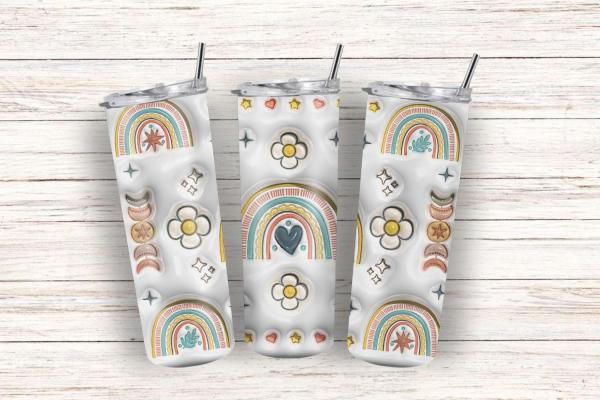 Drei Boho-Tumbler mit bunten Regenbogen-, Blumen- und Sternmotiven auf einem cremefarbenen Hintergrund, präsentiert auf einer rustikalen Holzoberfläche. Perfekt für trendbewusste Trinkliebhaber.