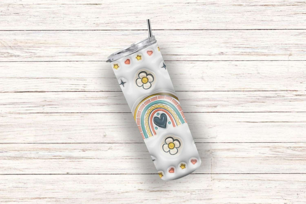 Einzelner Boho-Tumbler mit bunten Regenbogen-, Blumen-, Herz- und Sternmotiven auf einem cremefarbenen Hintergrund, liegend auf einer rustikalen Holzoberfläche. Stilvolles Design für trendige Trinkliebhaber.