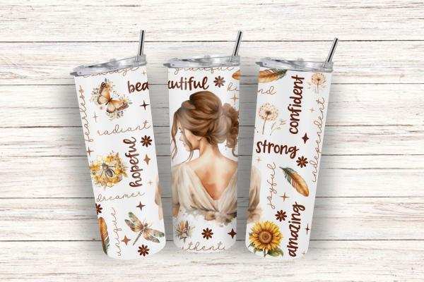 Drei weiße Thermobecher mit Illustrationen einer Frau von hinten, umgeben von Naturmotiven wie Schmetterlingen, Sonnenblumen, Federn und inspirierenden Worten wie 'beautiful', 'hopeful', 'strong' und 'confident'. Hintergrund aus Holz für einen rustikalen