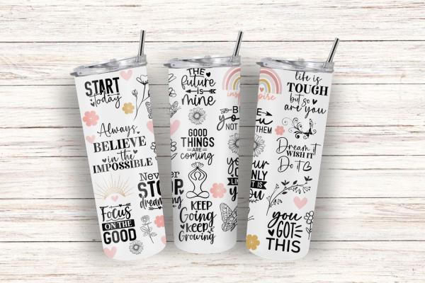 Drei weiße Thermobecher mit inspirierenden schwarzen Schriftzügen und Illustrationen, darunter Sprüche wie 'Believe in the impossible', 'Good things are coming', 'Focus on the good' und 'You got this'. Die Becher sind mit floralen Motiven und dezenten Pas