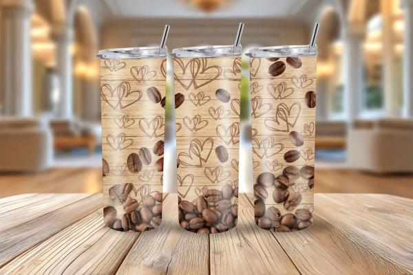 Drei Thermobecher mit einem Design aus holzähnlichem Hintergrund, gezeichneten Herzen und verstreuten Kaffeebohnen, die sich am unteren Rand sammeln. Die Becher stehen auf einem Holztisch vor einem elegant eingerichteten, unscharfen Raum, was eine warme u
