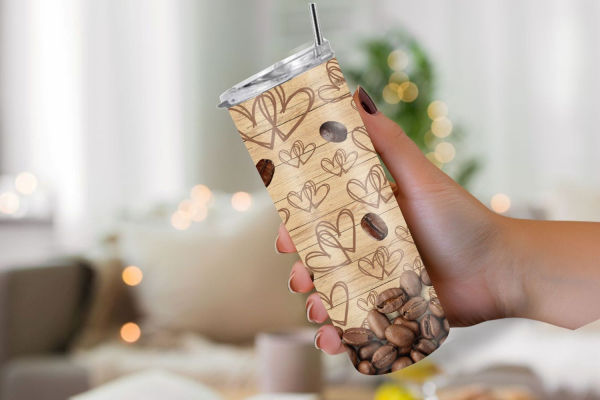 Hand hält einen Thermobecher mit einem holzähnlichen Design, verziert mit gezeichneten Herzmotiven und Kaffeebohnen, die sich am unteren Rand sammeln. Der Hintergrund zeigt einen gemütlichen Raum mit sanfter Beleuchtung, was eine warme Atmosphäre vermitte