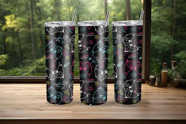Drei schlanke Thermobecher mit schwarzem Hintergrund und lebendigem Gaming-Design. Die Becher sind mit weißen Skizzen von Spielcontrollern und farbigen Texten wie ‚Press Start‘, ‚Game Over‘, ‚Loading‘, ‚Never Give Up‘ in Neonfarben wie Blau, Rosa und Gelb