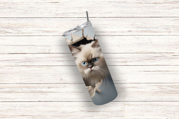Thermobecher mit einem verspielten Design einer flauschigen weißen Katze mit blauen Augen, die durch ein realistisches Loch in der Oberfläche schaut. Der Becher hat eine matte, graue Hintergrundfarbe, die die Details der Katze hervorhebt. Die Holzhintergr