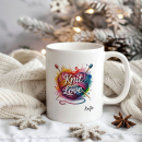 Weißer Keramikbecher mit farbenfrohem Motiv Knit with Love, personalisiert mit Namen, dekoriert vor winterlichem Hintergrund mit Strickdecke und Weihnachtsdetails.